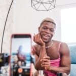 Transgender beauty content creator applying makeup to mobile phone camera